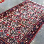 Rectangular rug with ivory field, dark navy border, and repeating red-blue medallions
