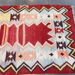 Turkish kilim rug with red and cream chevrons, multicolor accents, and fringe