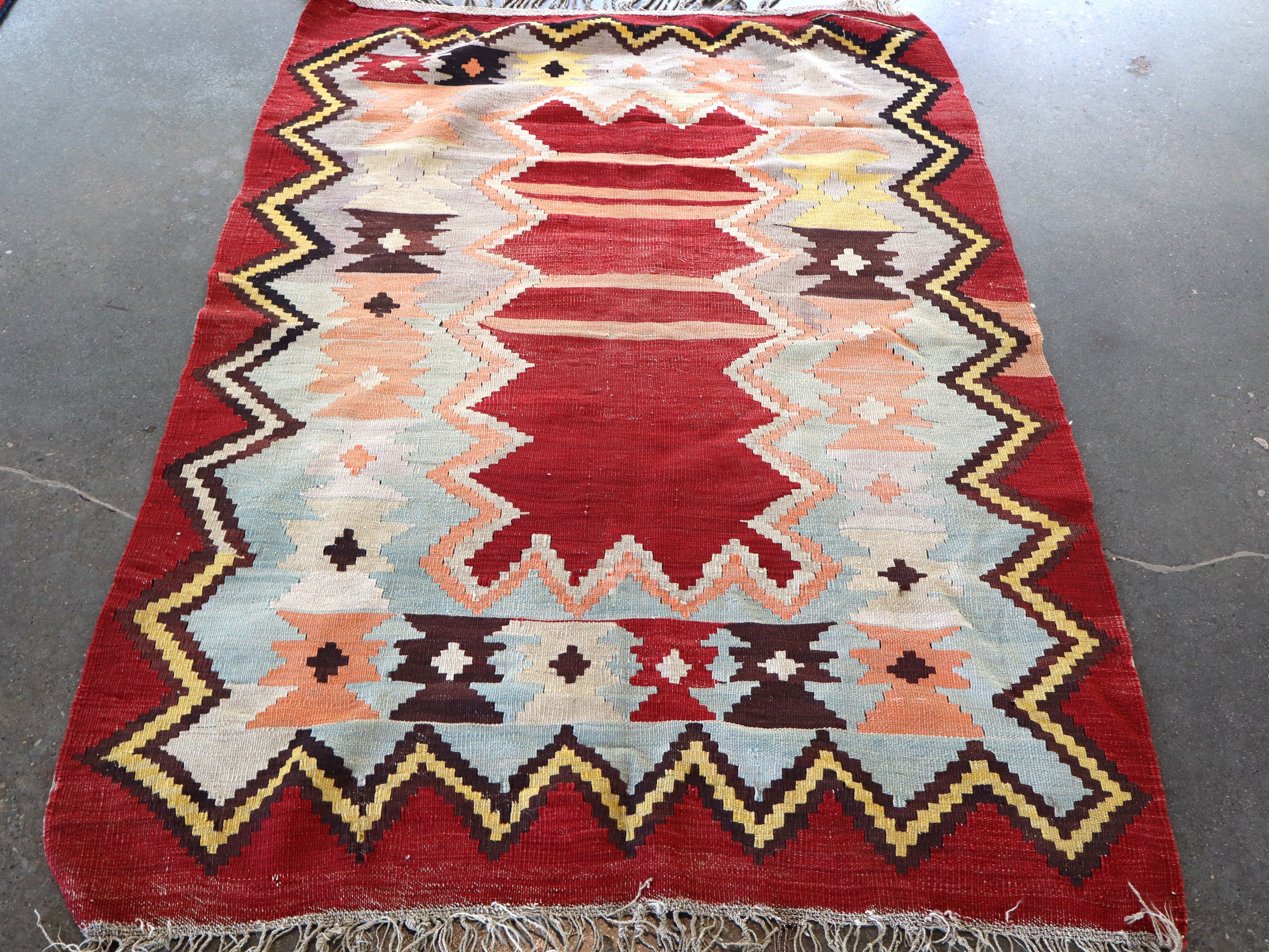 Red Turkish kilim rug with geometric zigzag patterns in cream, light blue, and black