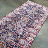 Fine Persian Kirman runner rug angled view with navy and red floral motifs