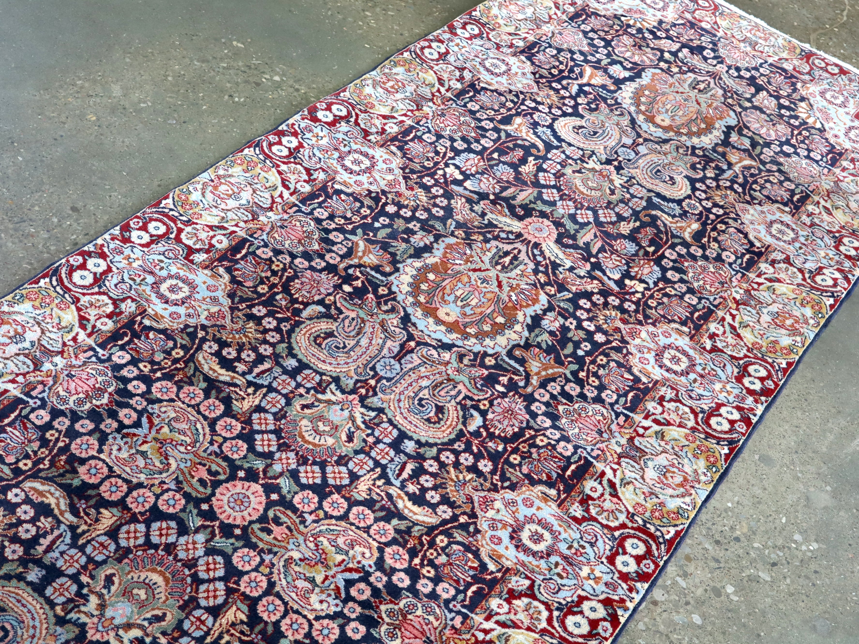 Fine Persian Kirman runner rug diagonal view with navy field and red medallion accents