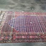 Persian Malayer rug diagonal view with navy patterned field and red outer band
