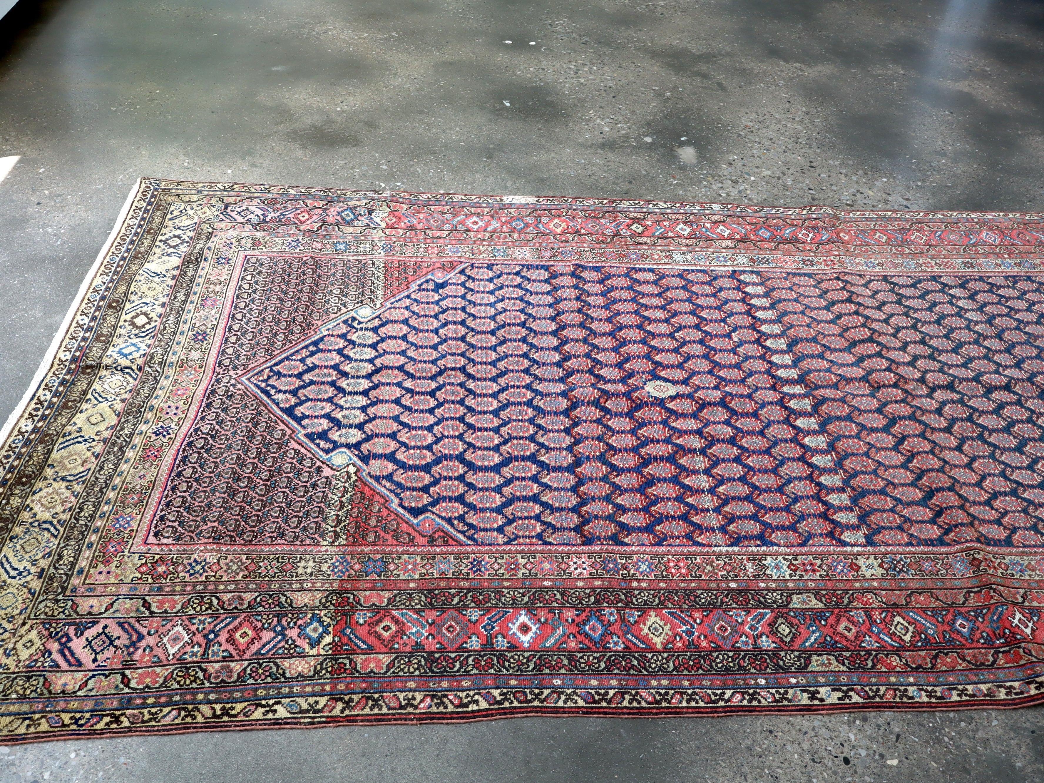 Persian Malayer rug diagonal view with navy patterned field and red outer band