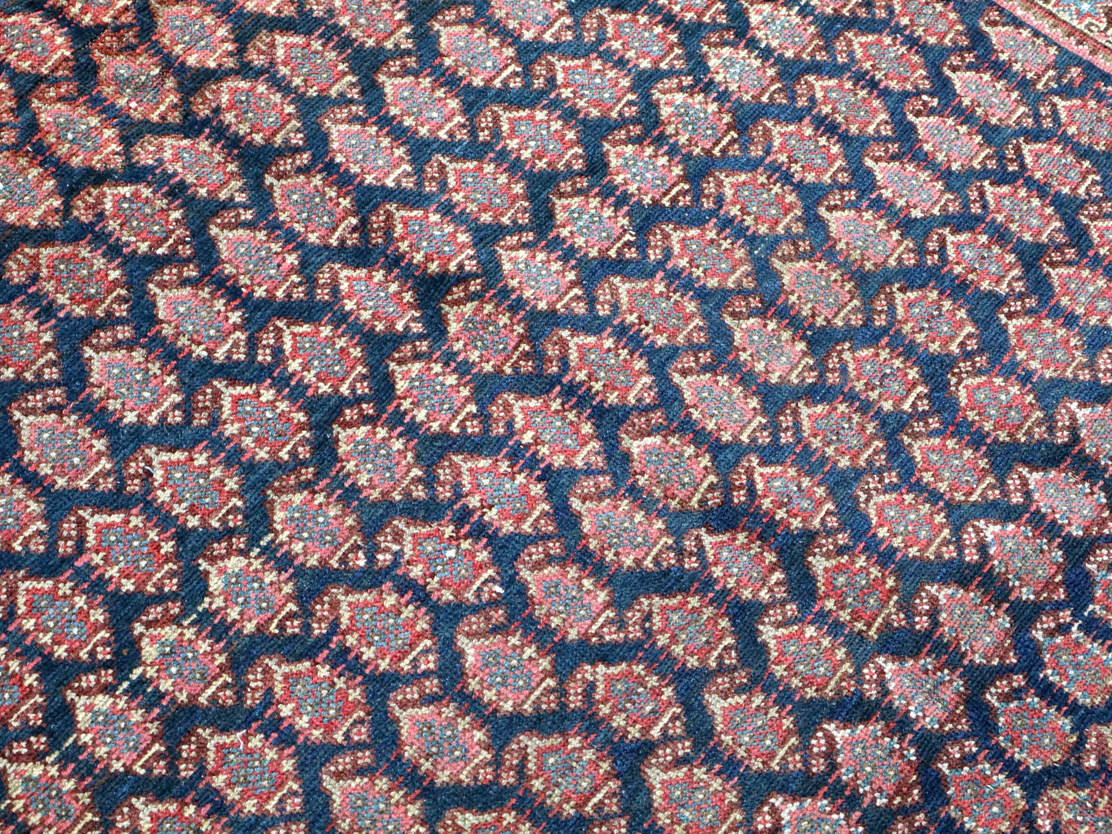 Close-up texture of Persian Malayer rug navy field with red and cream accents