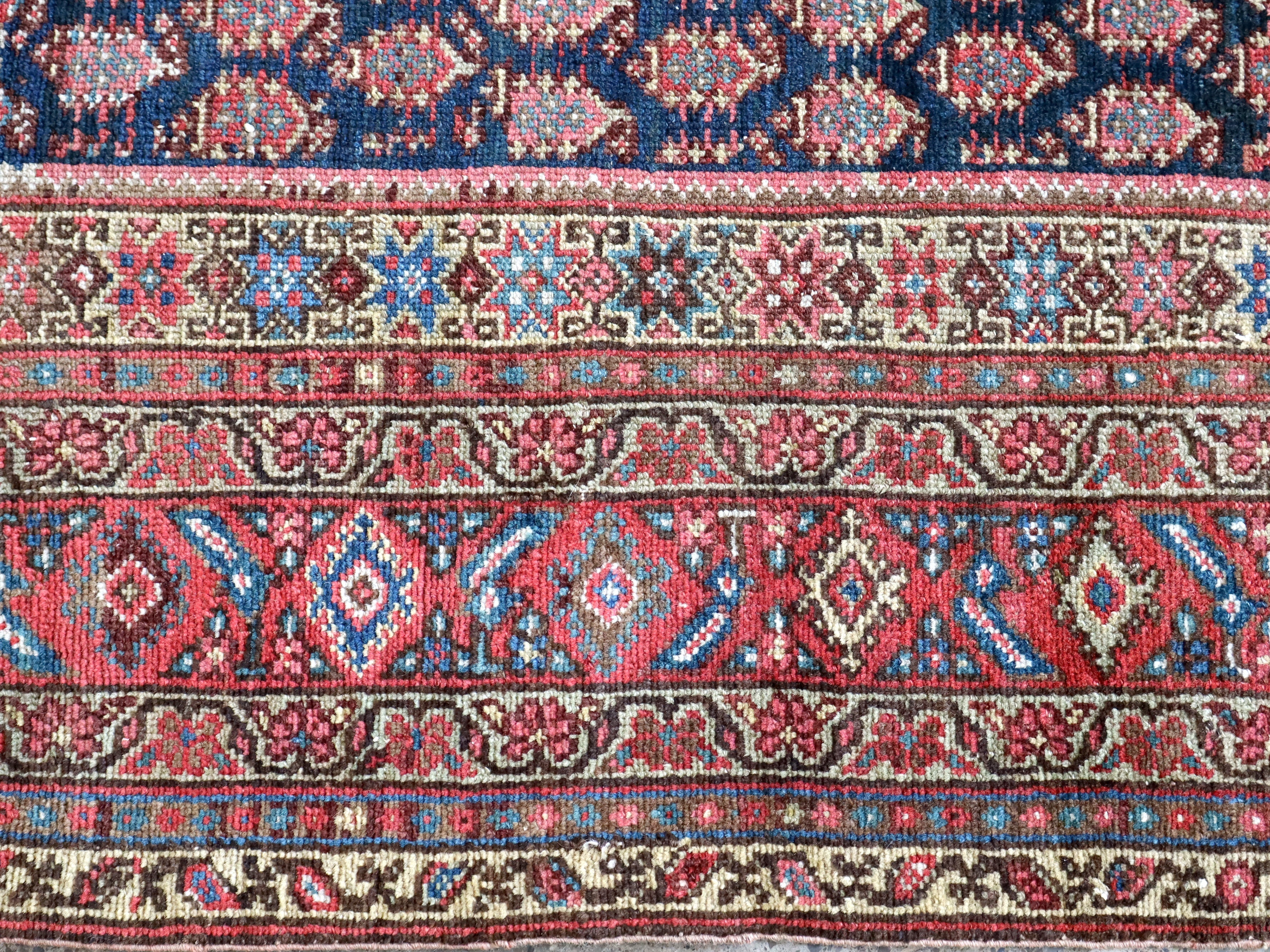 Malayer rug border with red-blue diamonds and cream decorative stripes