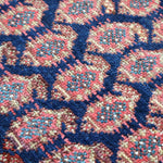 Malayer rug close-up of blue, red, and cream repeating diamond pattern