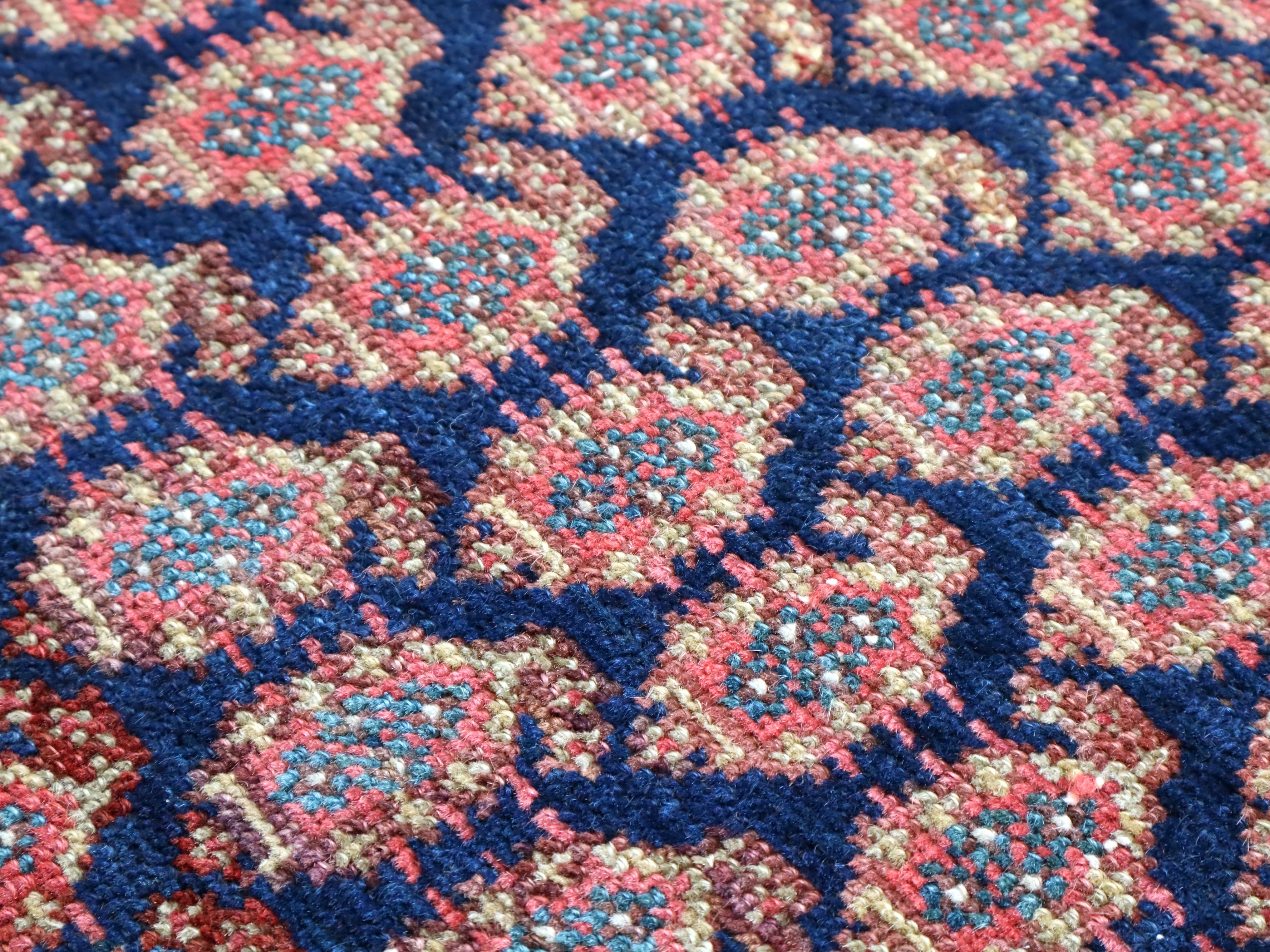 Malayer rug close-up of blue, red, and cream repeating diamond pattern