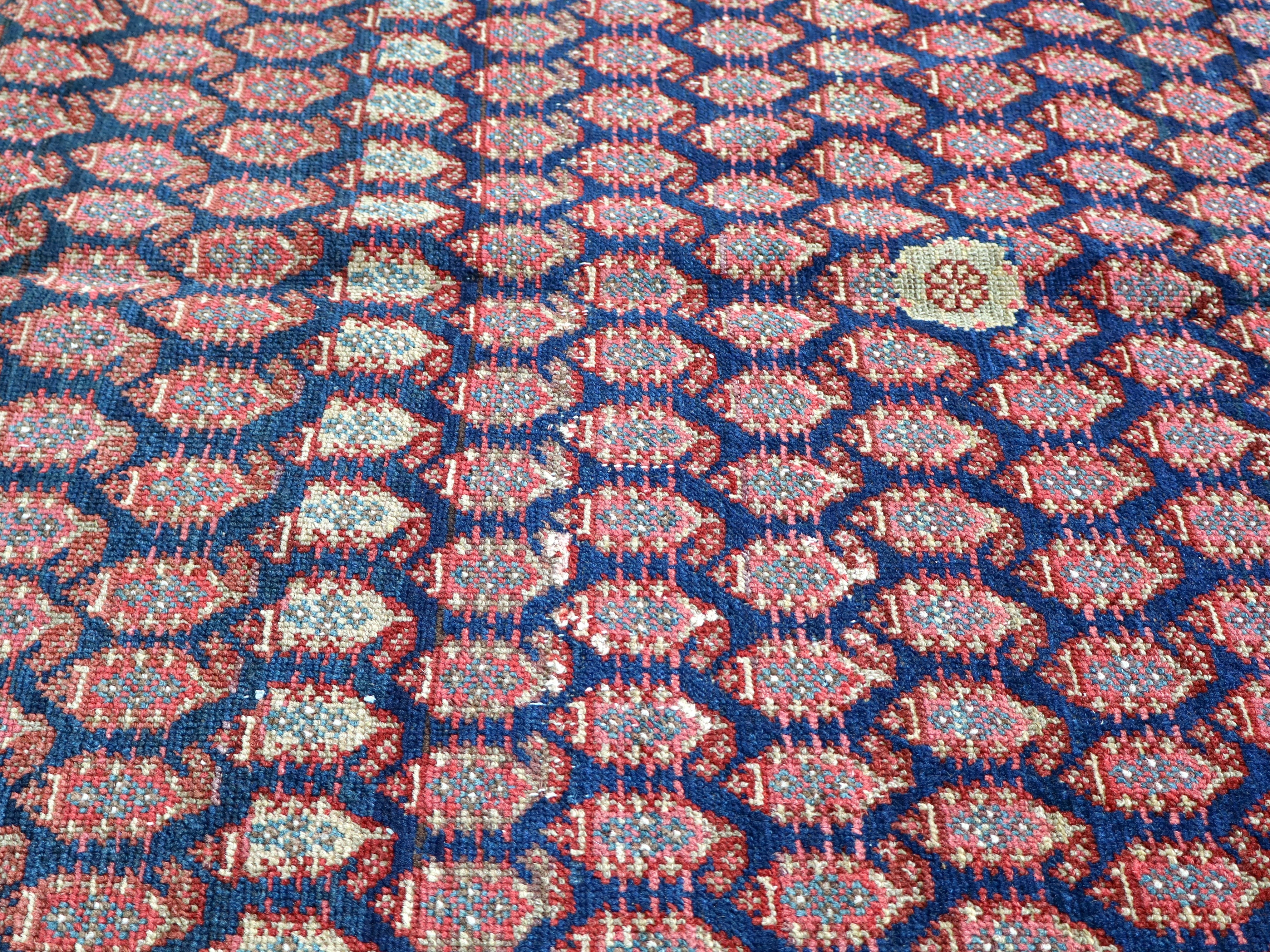 Malayer rug surface with red, blue, and cream star and diamond motifs