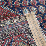 Malayer rug close-up showing cream border band and blue-red geometric motifs