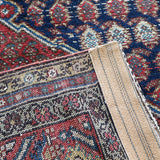 Malayer rug close-up showing cream border band and blue-red geometric motifs