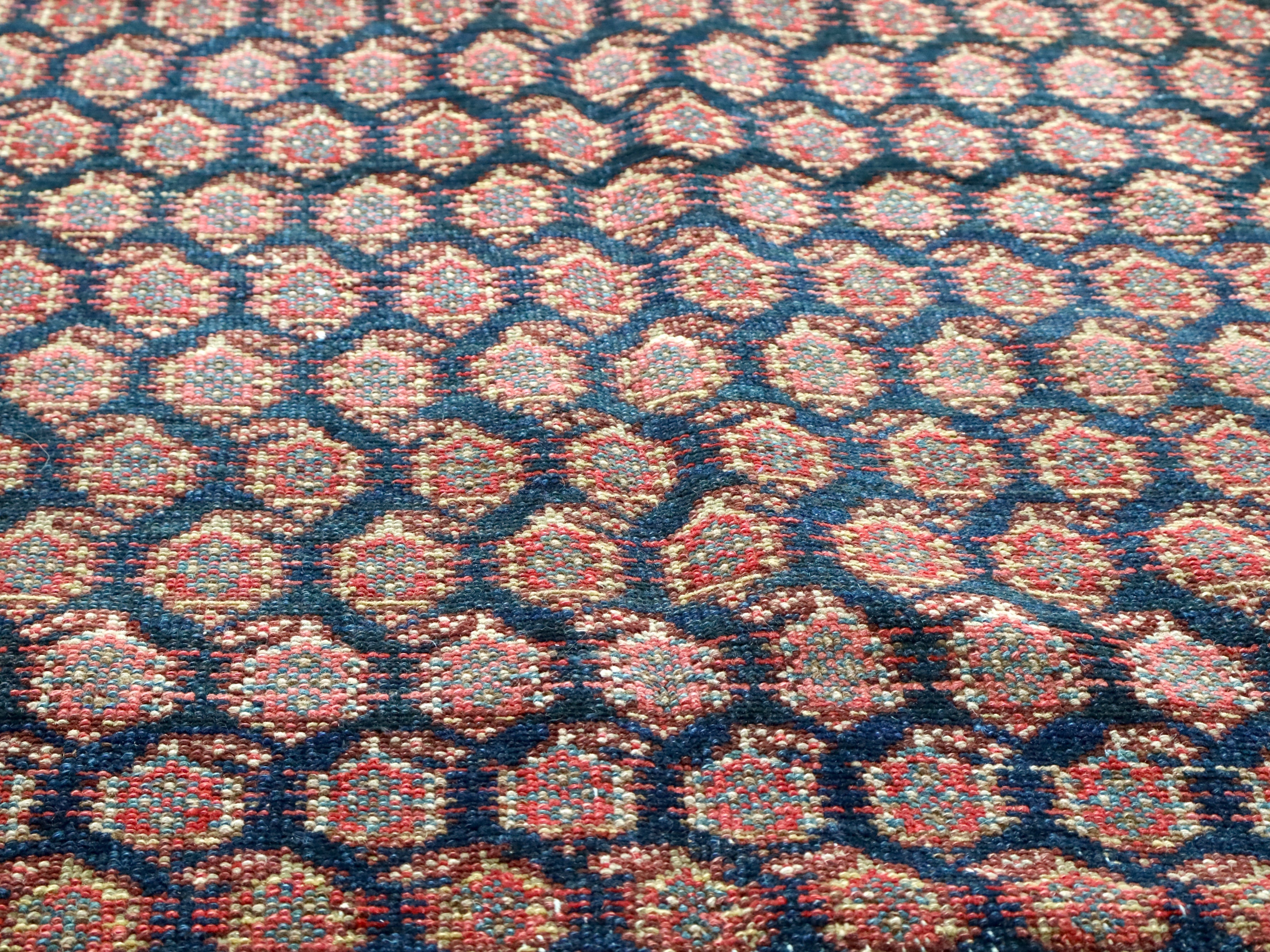 Malayer rug close-up of dense blue, red, and cream geometric pattern