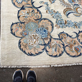 Persian Kashan rug corner detail with layered blue, tan, and gold floral design; fringe