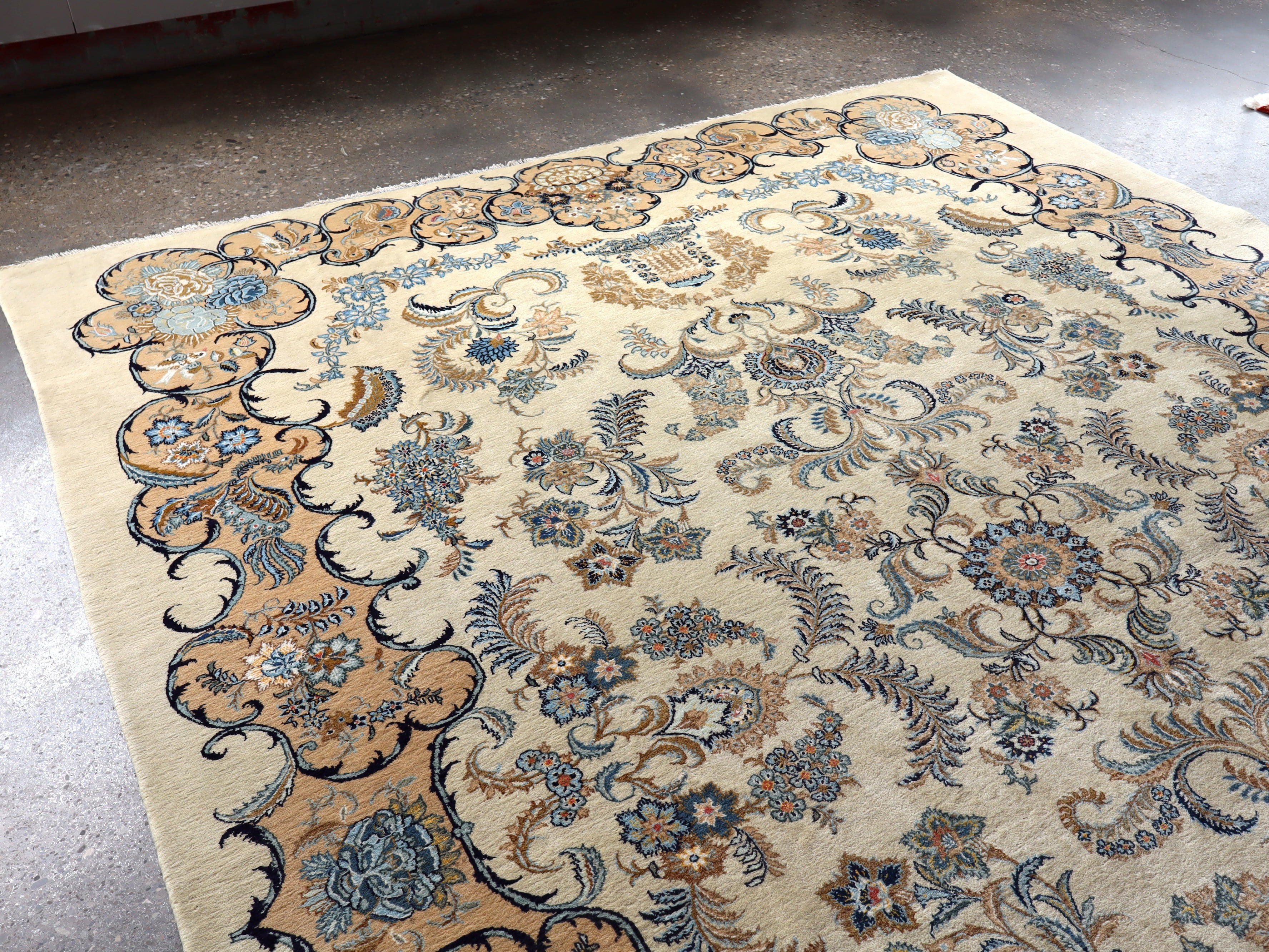 Persian Kashan rug with ivory field and blue floral swirls; decorative corner elements