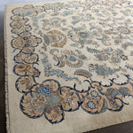 Persian Kashan rug with cream background and dark navy scroll border; floral cluster