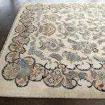 Persian Kashan rug with light cream field and blue floral medallion; scrolling border