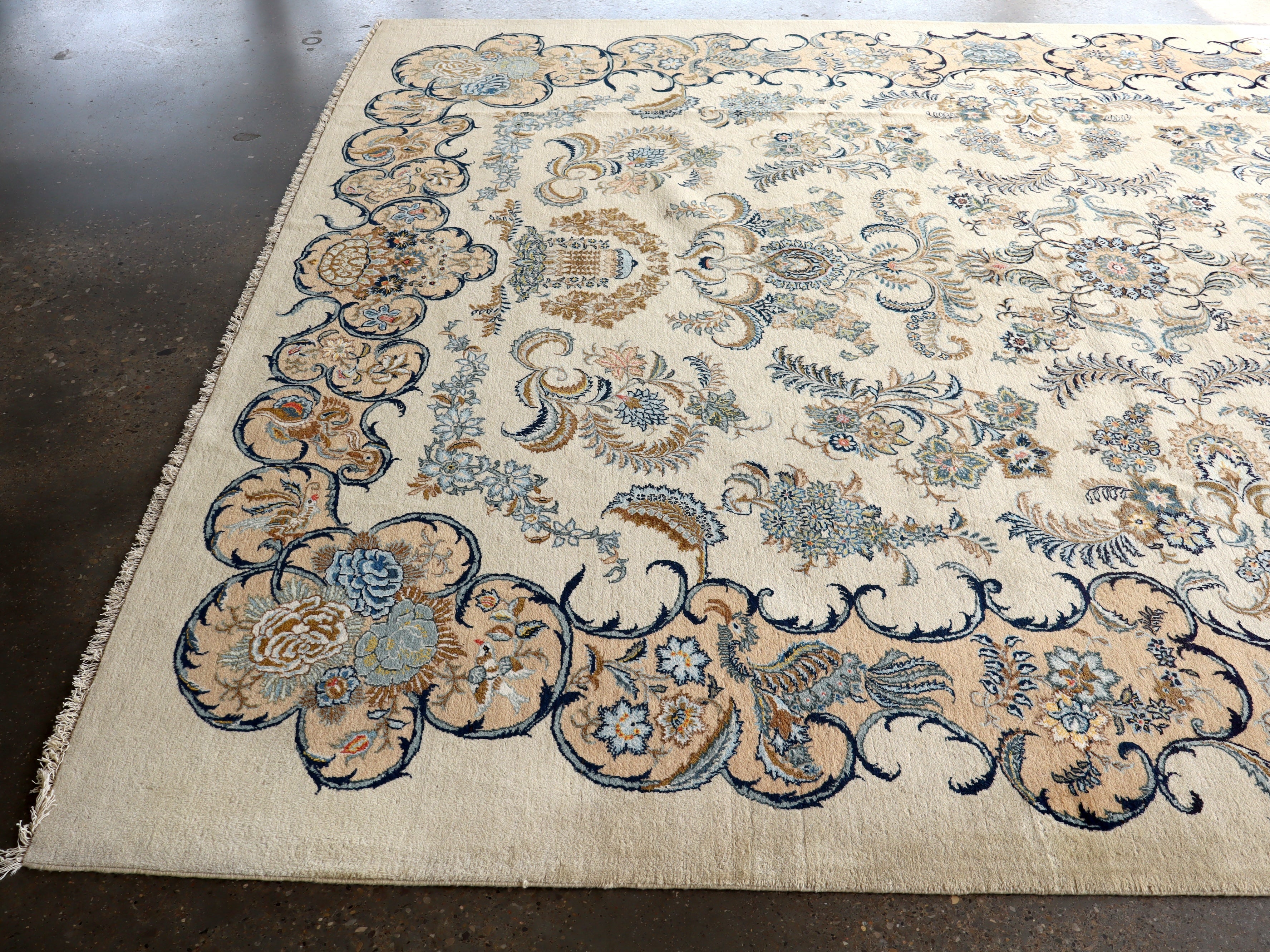 Persian Kashan rug with light cream field and blue floral medallion; scrolling border