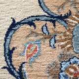 Persian Kashan rug close-up corner: ivory ground with navy scroll line and small florals