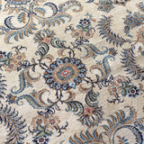 Persian Kashan rug close-up with blue, teal, and tan leaf motifs around a central flower