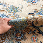 Persian Kashan rug with blue floral medallions and cream base, close-up texture