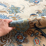 Persian Kashan rug with blue floral medallions and cream base, close-up texture
