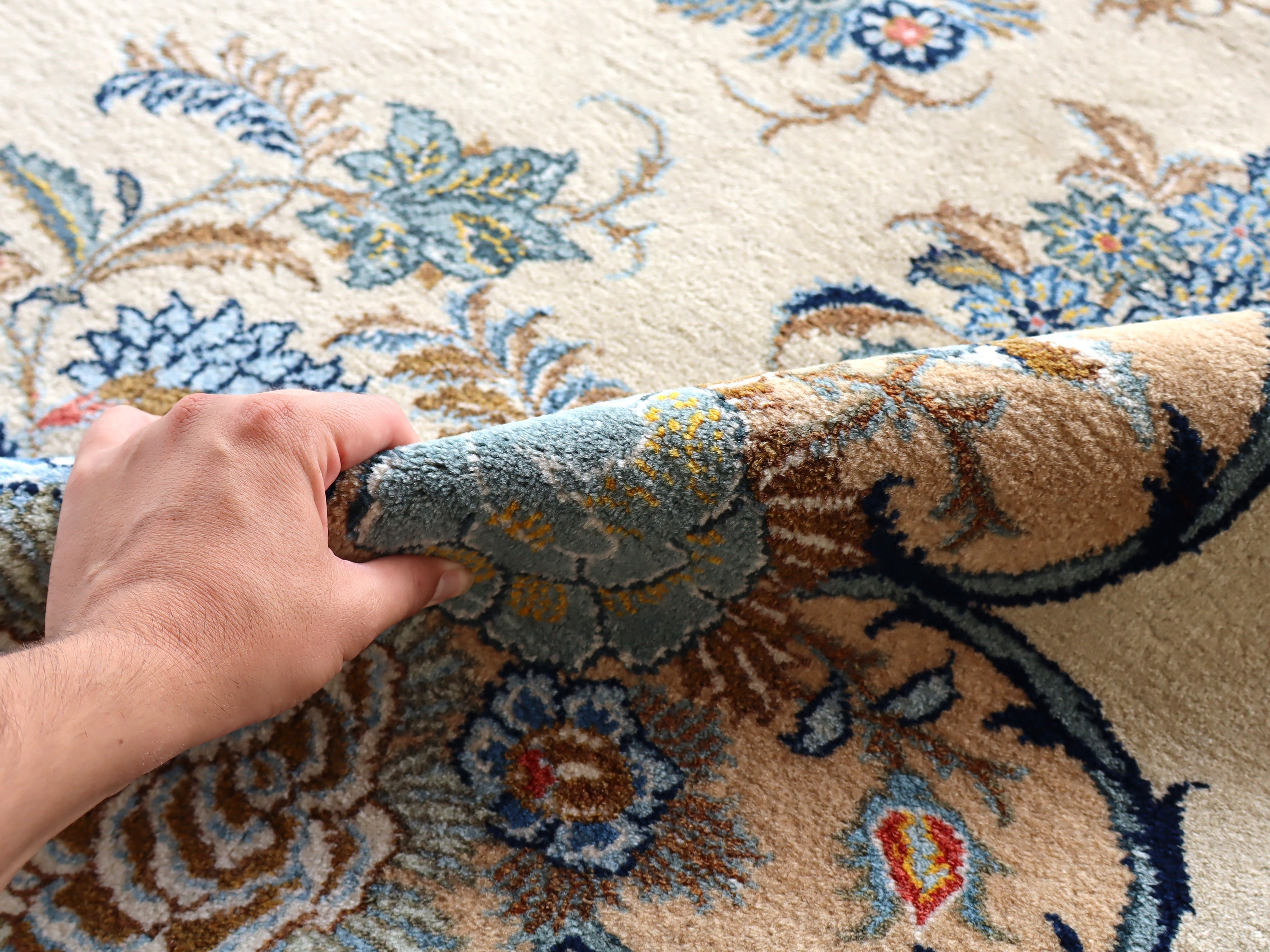 Persian Kashan rug with blue floral medallions and cream base, close-up texture