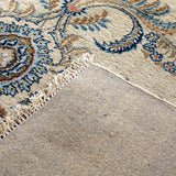 Persian Kashan rug corner with fringed edge and speckled cream pile, blue accents