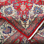 Persian Tabriz rug with red field, cream corner motifs, and decorative border with fringe