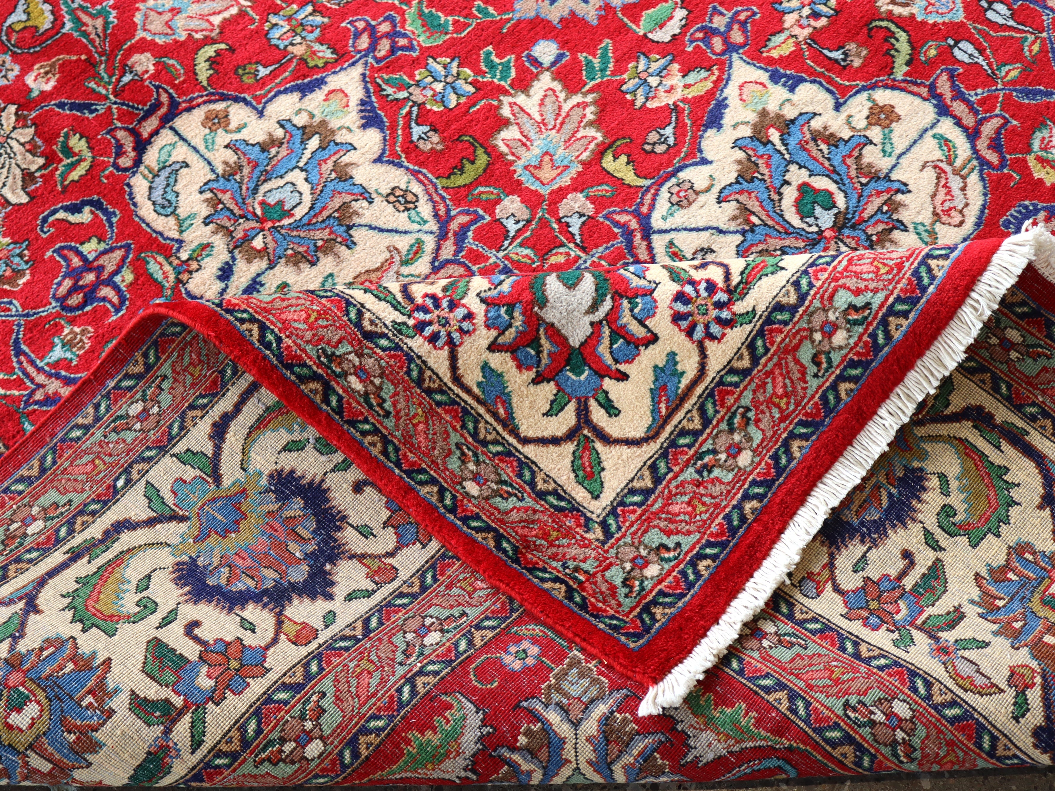 Persian Tabriz rug with red field, cream corner motifs, and decorative border with fringe