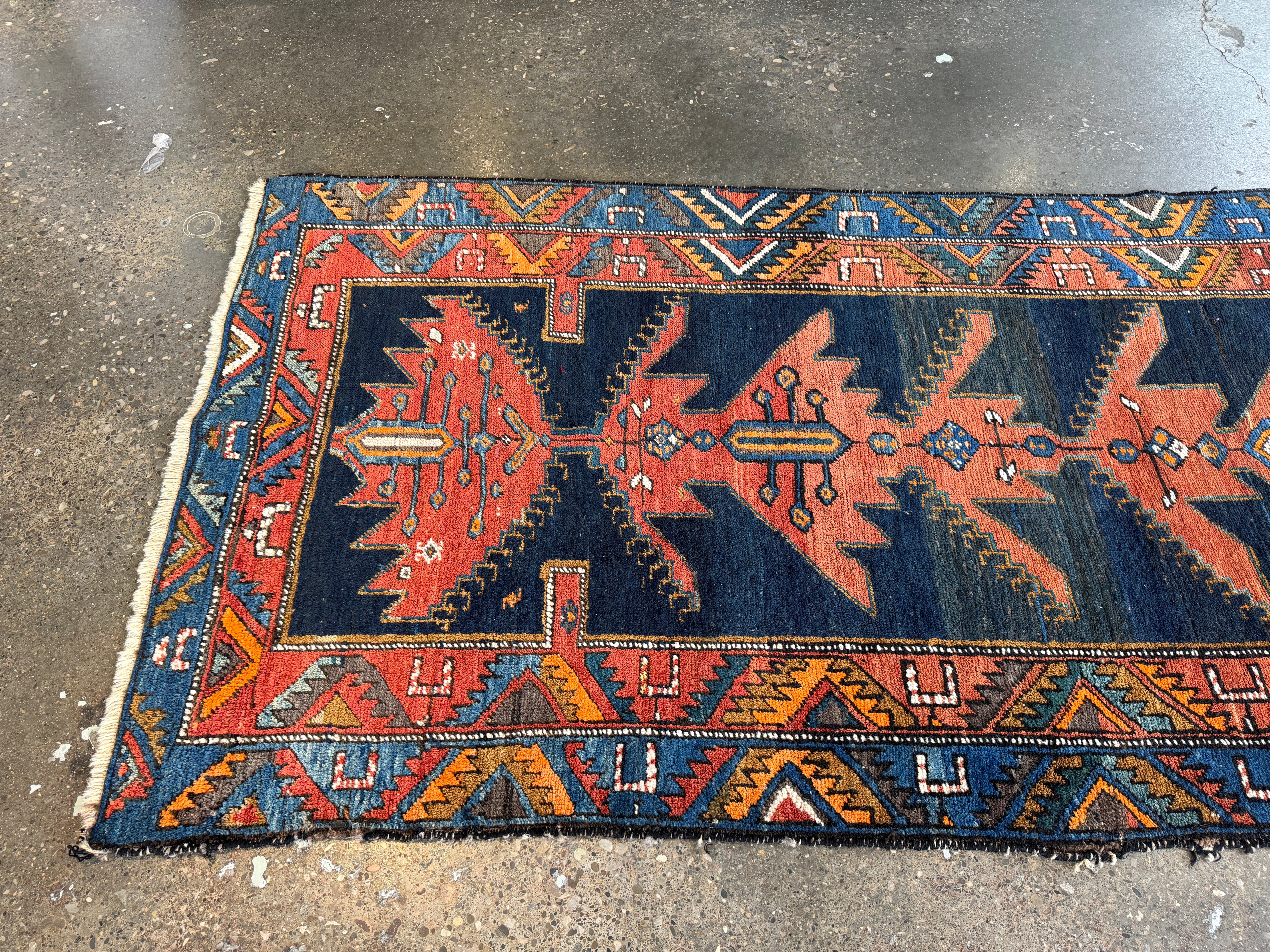 Persian runner rug with dark navy, rust, and teal geometric motifs, fringed ends