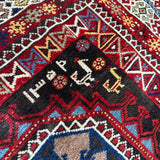 Runner rug close-up with red, navy and cream peaked motifs and blue central medallion.