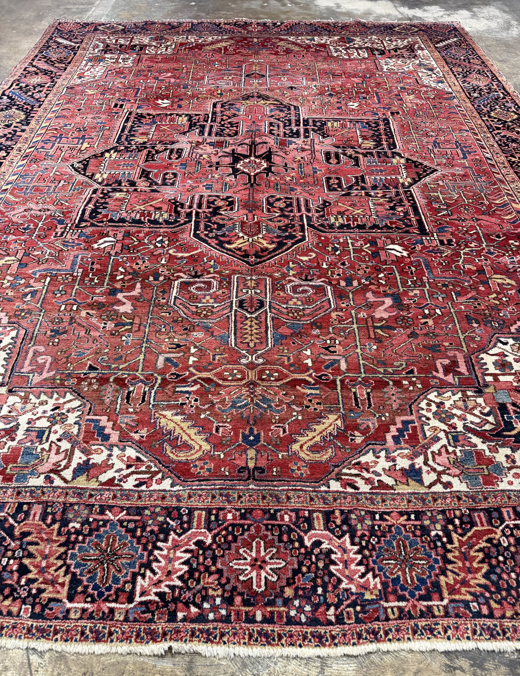 Persian Heriz rug showing large central medallion on red, with ornate geometric bands.