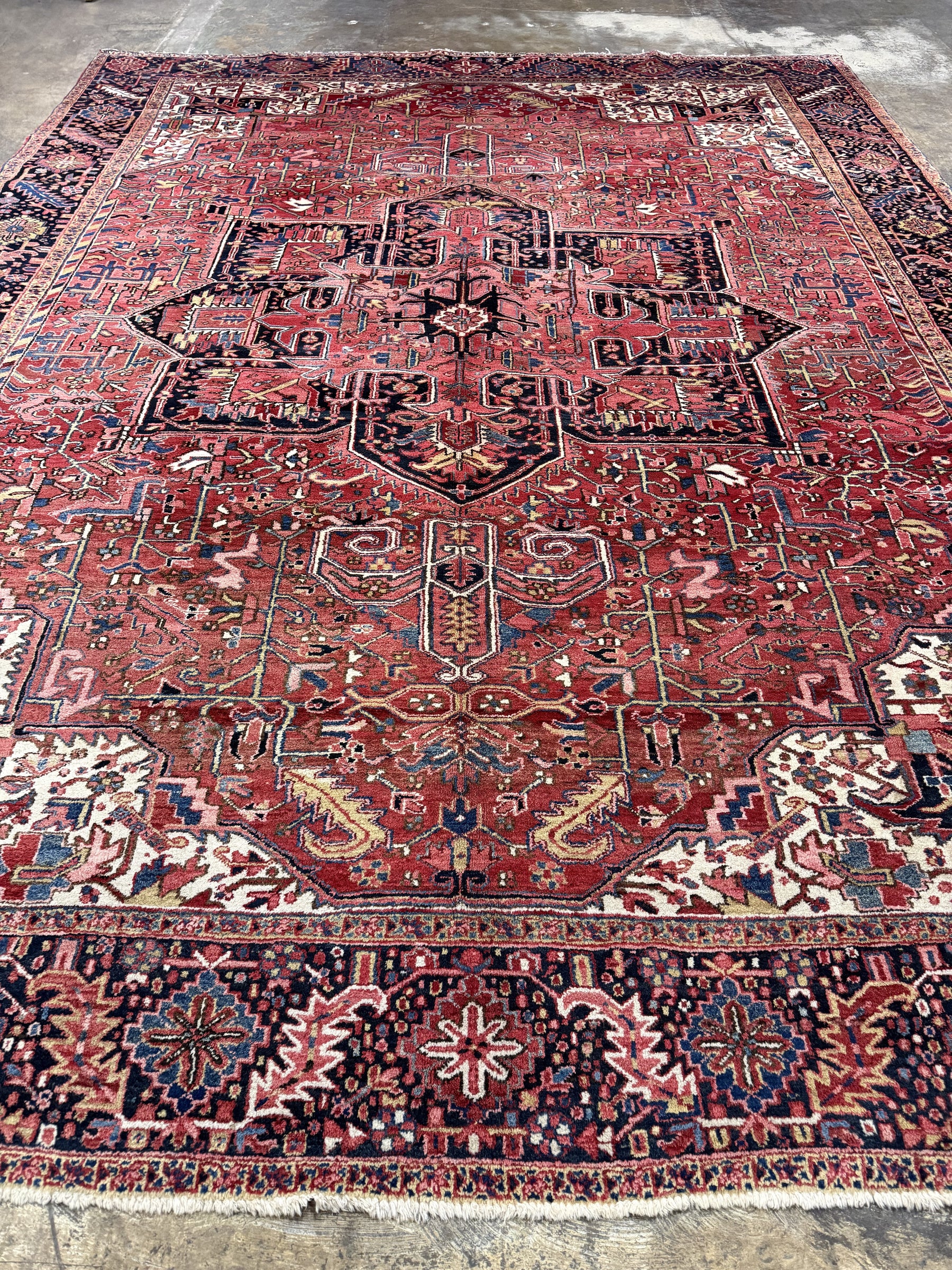 Persian Heriz rug showing large central medallion on red, with ornate geometric bands.