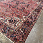Persian Heriz rug with red ground, navy and cream medallion, geometric border detail.