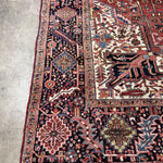 Persian Heriz rug edge with red border stripe, navy motifs, cream accents, and short fringe.