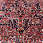 Persian Heriz rug pattern close-up with red and navy geometric forms and central medallion.