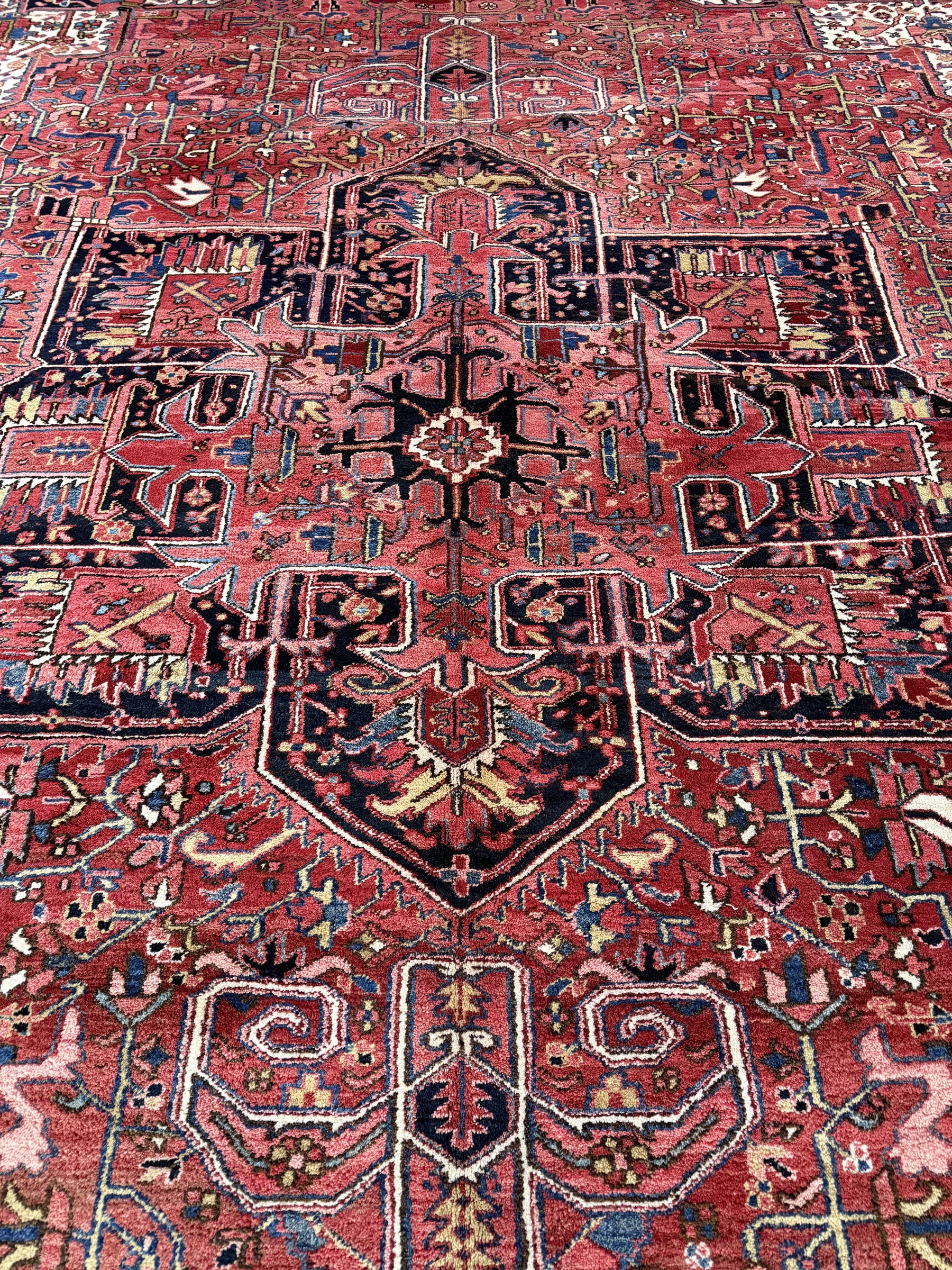 Persian Heriz rug pattern close-up with red and navy geometric forms and central medallion.
