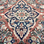 Persian-style rug with central blue-and-cream medallion on rust background, detailed florals