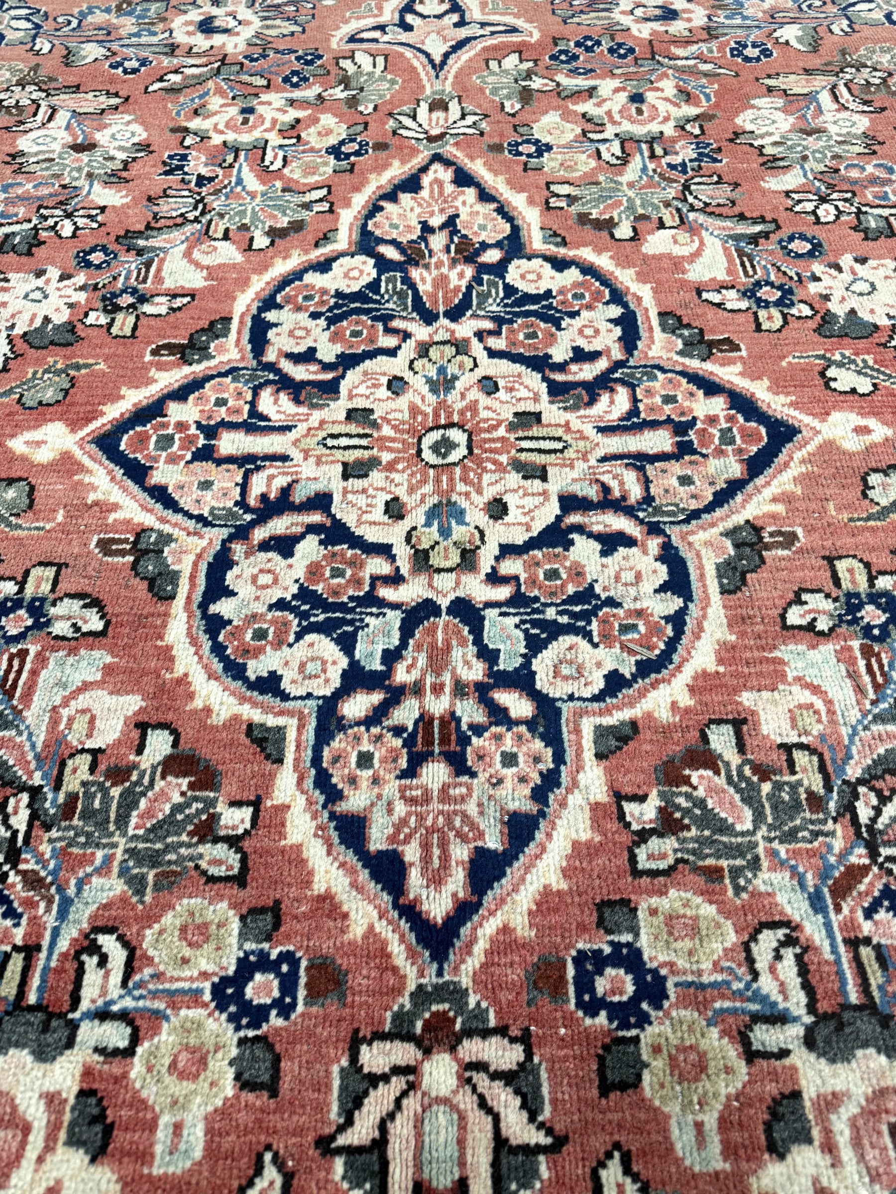 Persian-style rug with central blue-and-cream medallion on rust background, detailed florals