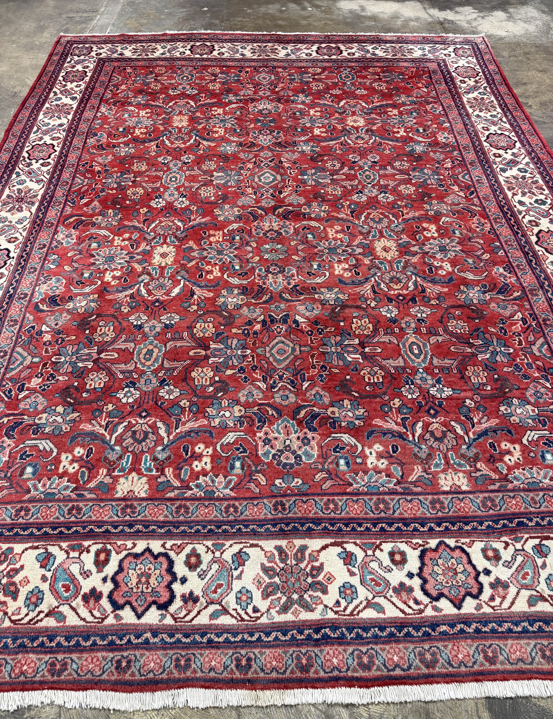 Persian Mahal-style area rug, red field with ornate motifs and cream border fringe.