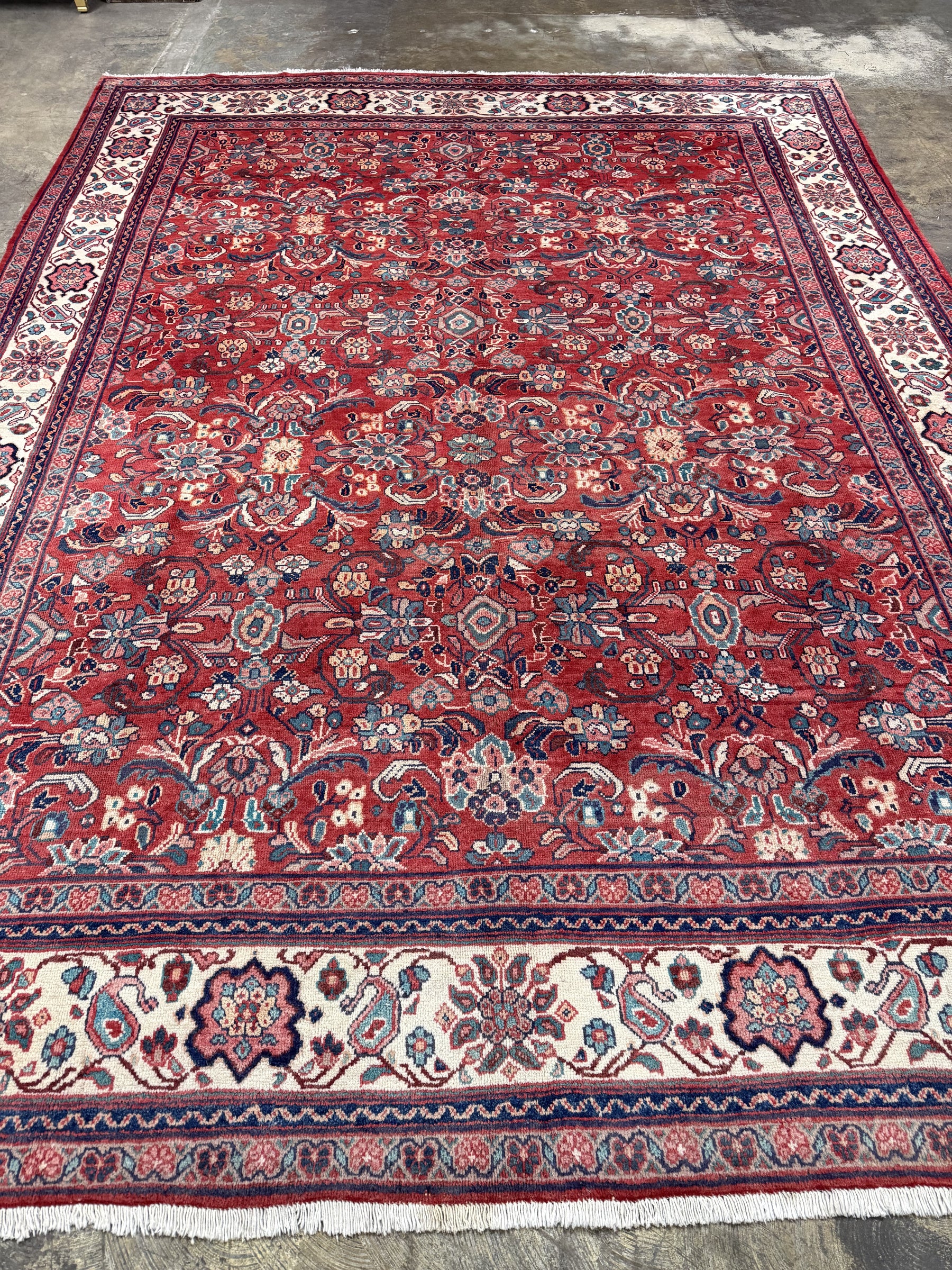 Persian Mahal-style area rug, red field with ornate motifs and cream border fringe.