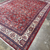 Persian Mahal-style area rug with red pattern, navy edging, and cream geometric corner panels.