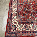 Persian Mahal-style rug edge with red field, cream panel, navy trim, and fringe.