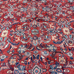 Persian Mahal-style rug close-up with red florals, blue accents, and multicolor medallions.