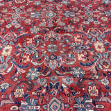 Persian Mahal-style rug close-up with red florals, blue accents, and multicolor medallions.
