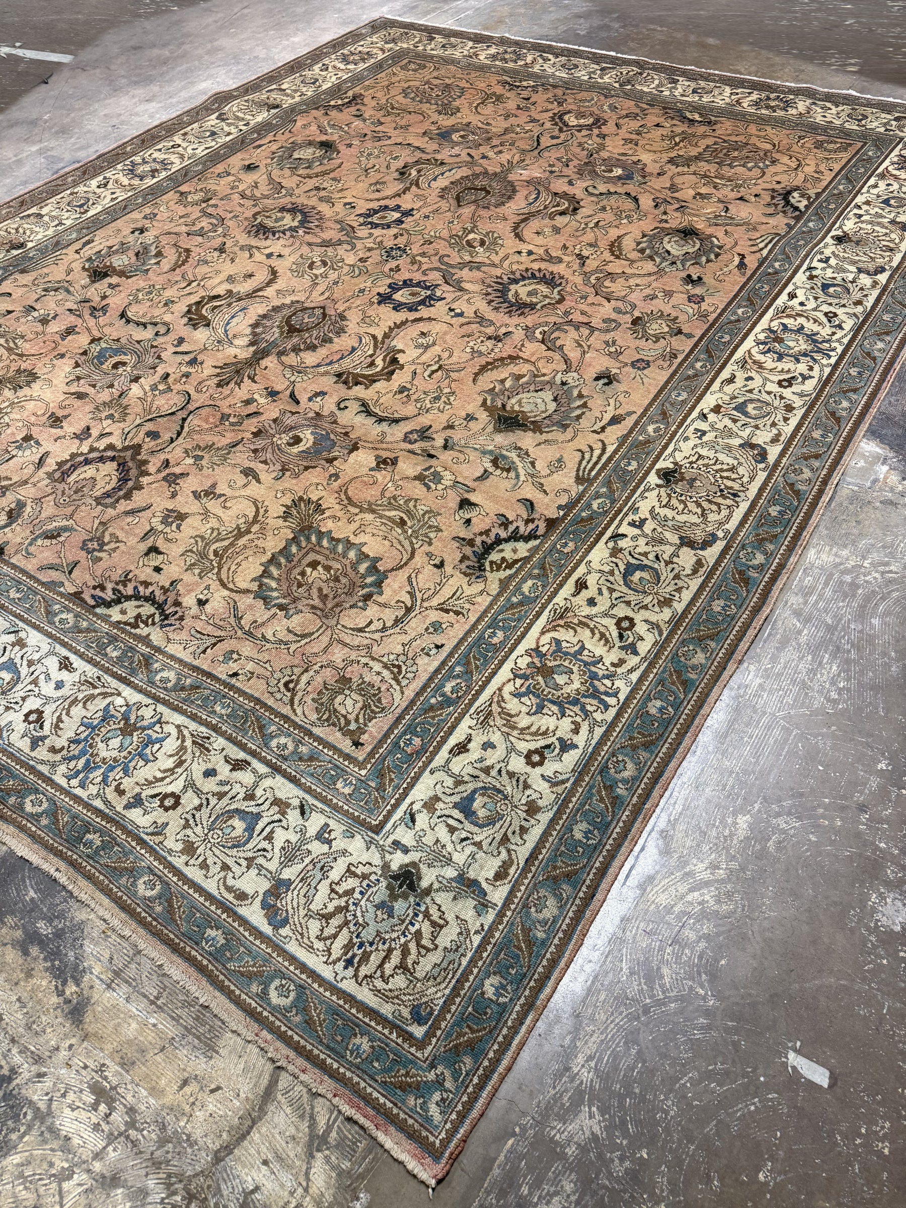 Persian Tabriz rug corner view, beige field with teal floral vines and ivory border