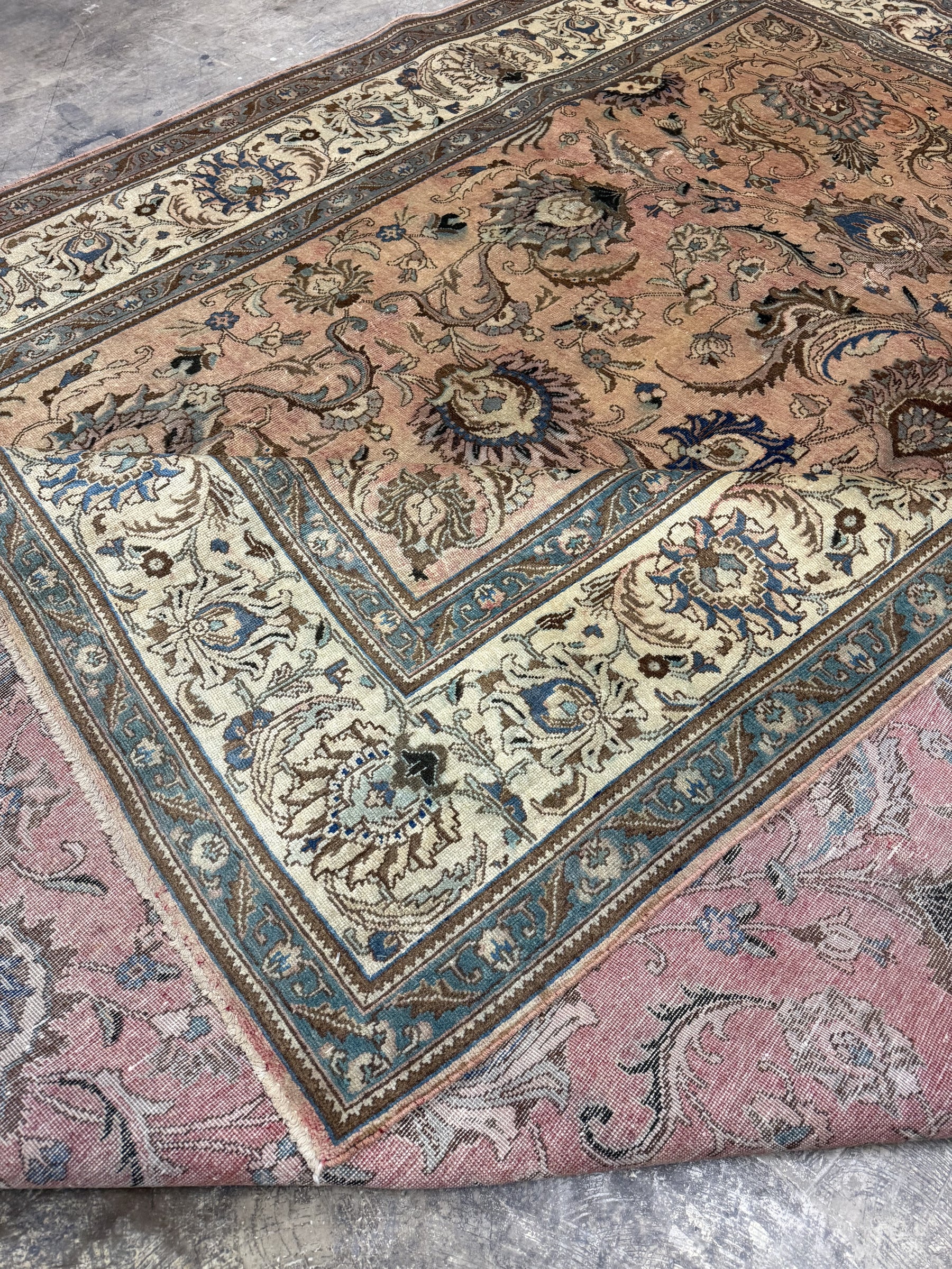 Persian Tabriz rug edge detail, pinkish-beige field with teal and cream ornamentation