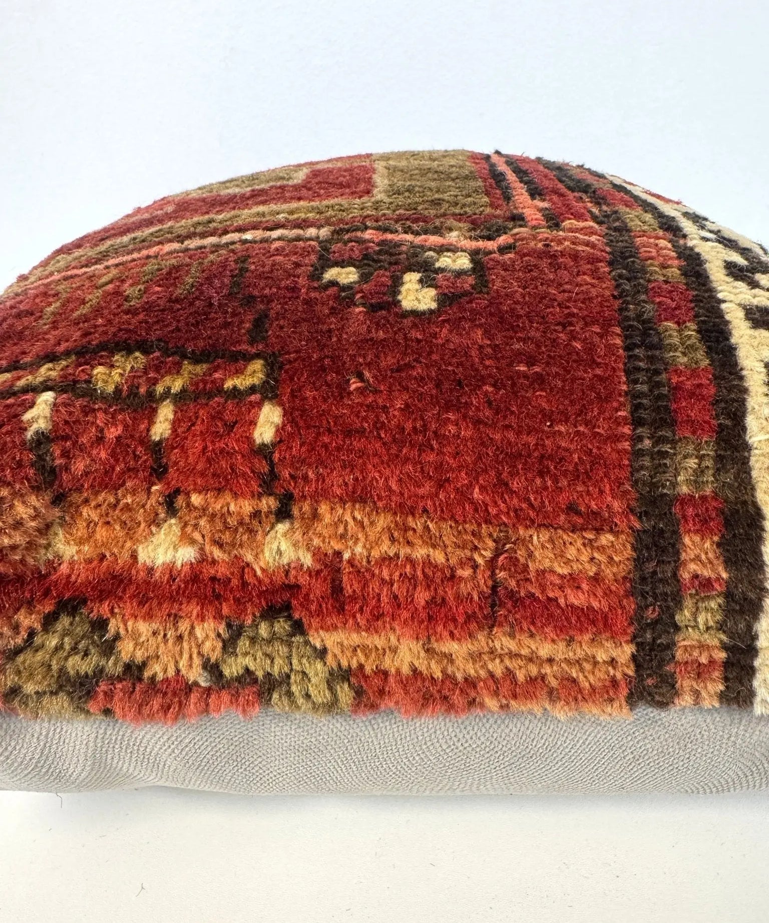 Woven pillow cover back edge with red, olive, and cream patterned stripes and fringed hem