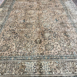 Tabriz-style rug with cream center and intricate blue floral corner motifs.
