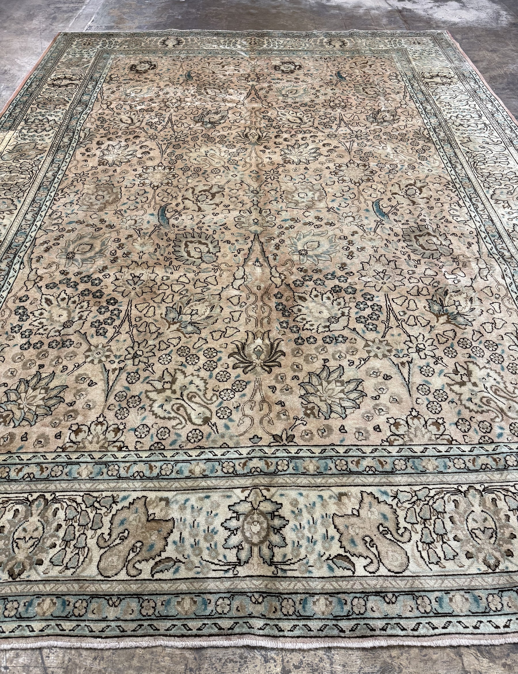 Tabriz-style rug with cream center and intricate blue floral corner motifs.