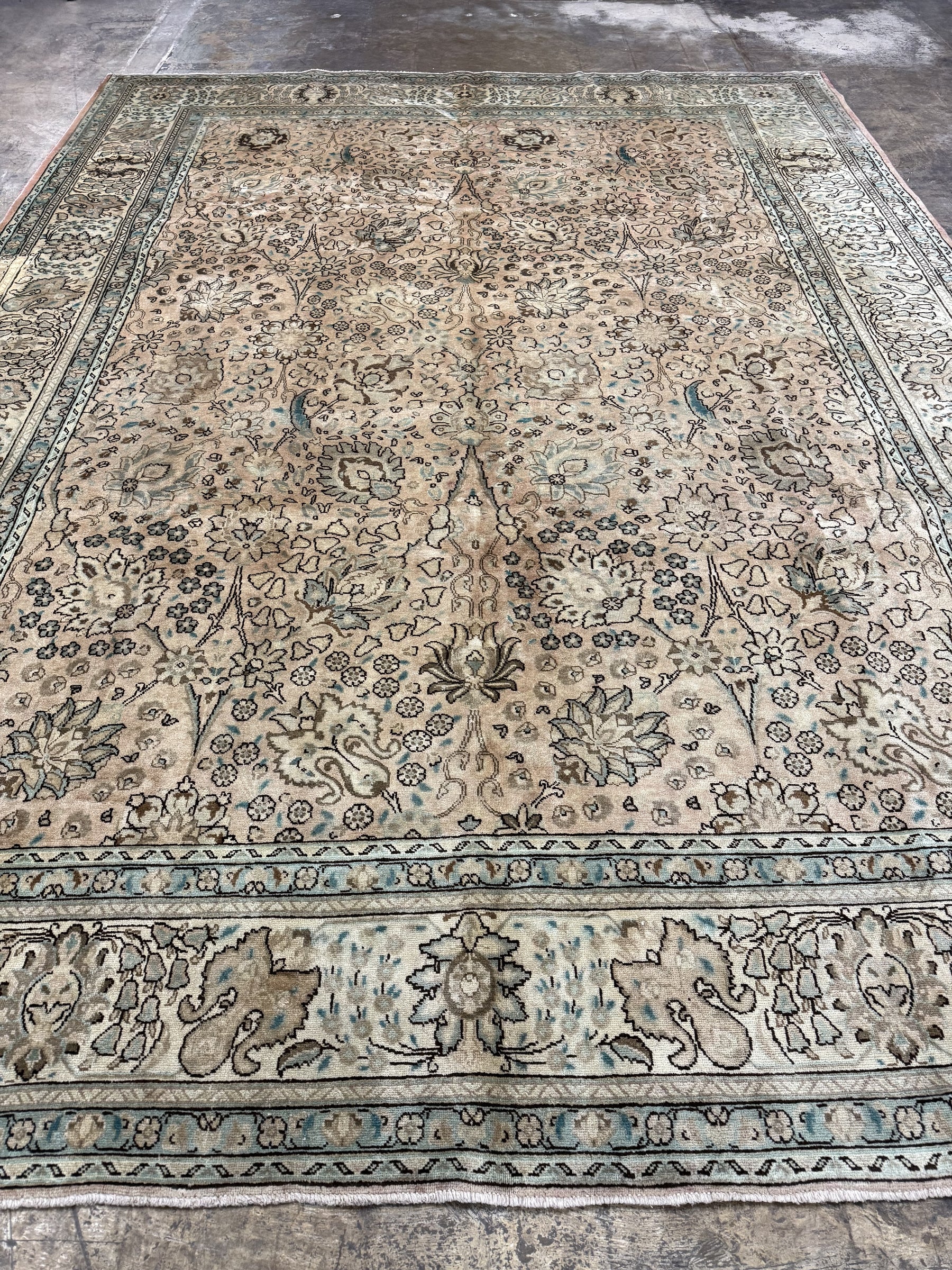 Tabriz-style rug with cream center and intricate blue floral corner motifs.